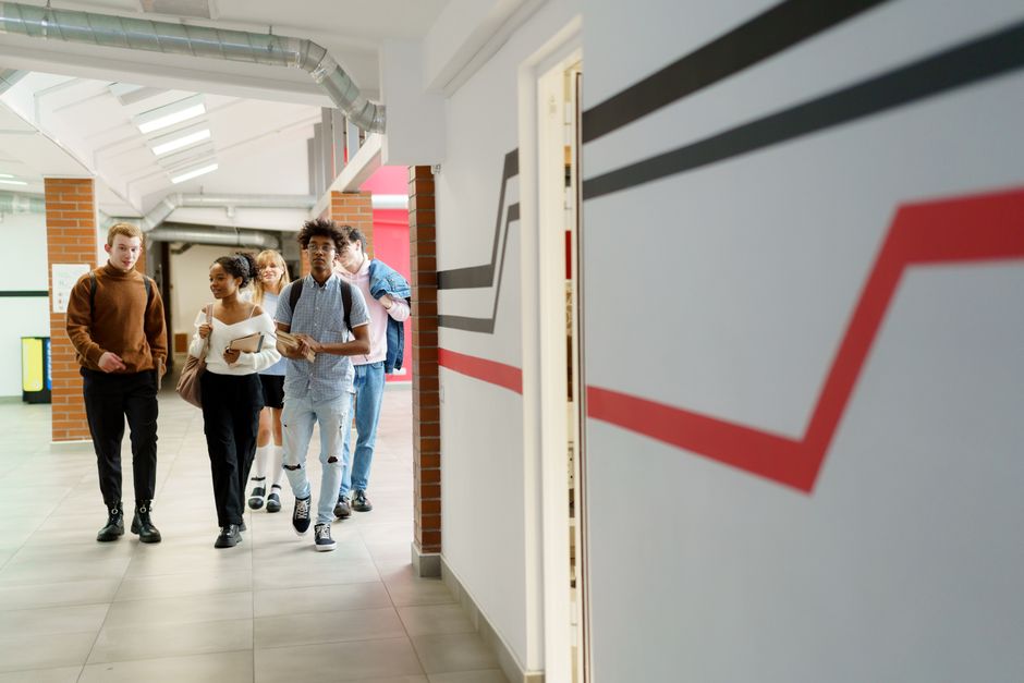 Educação Pública Brasil — A diverse group of teenagers walking together in a modern school hallway.